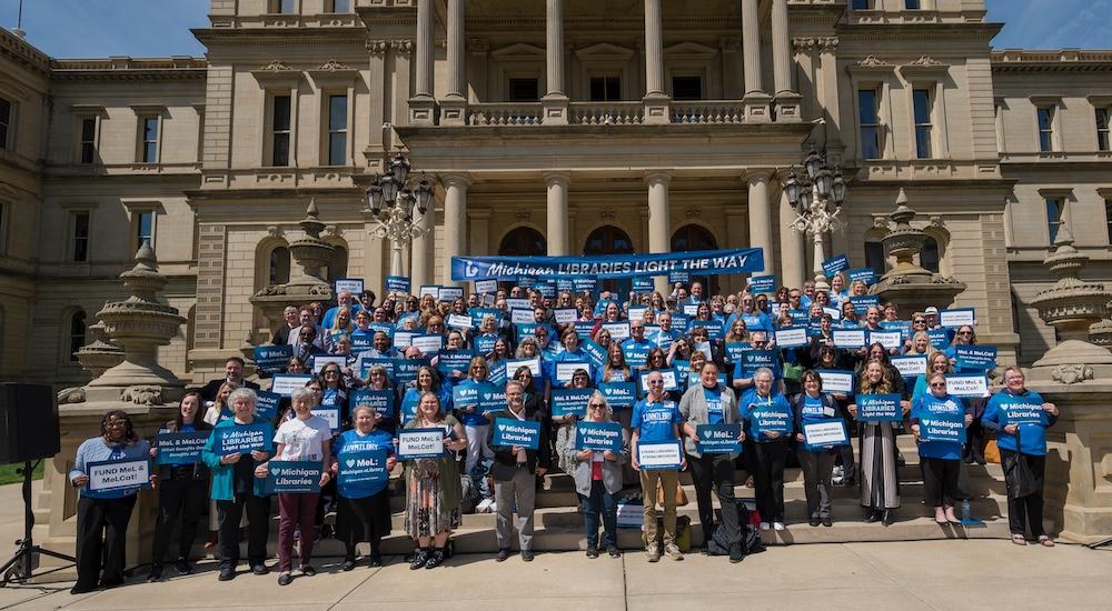 Advocacy Day 2025 attendees post with signs on the Capitol steps