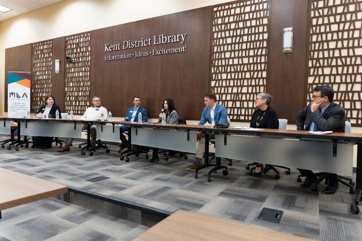 Roundtable panelists at a long table under the Kent District Library logo